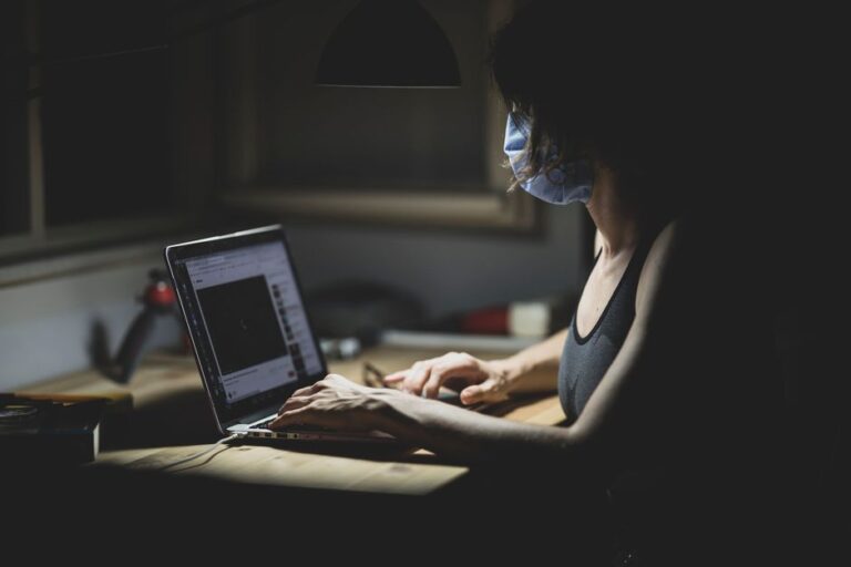 A person working at a desk with a laptop and soft, natural lighting from a nearby window.